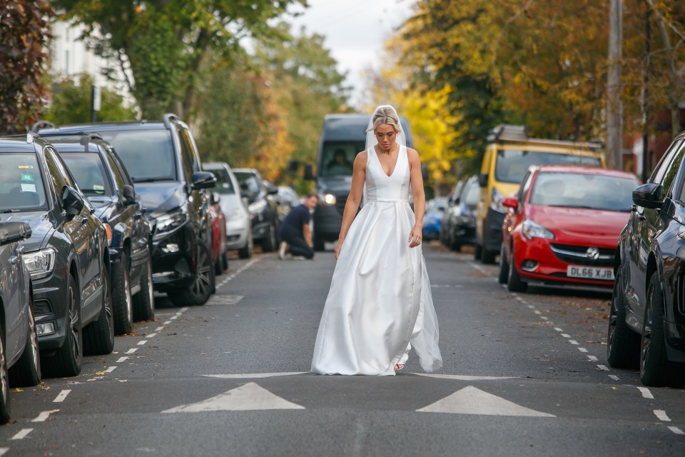 Bride walking down a residential street in a white wedding dress.