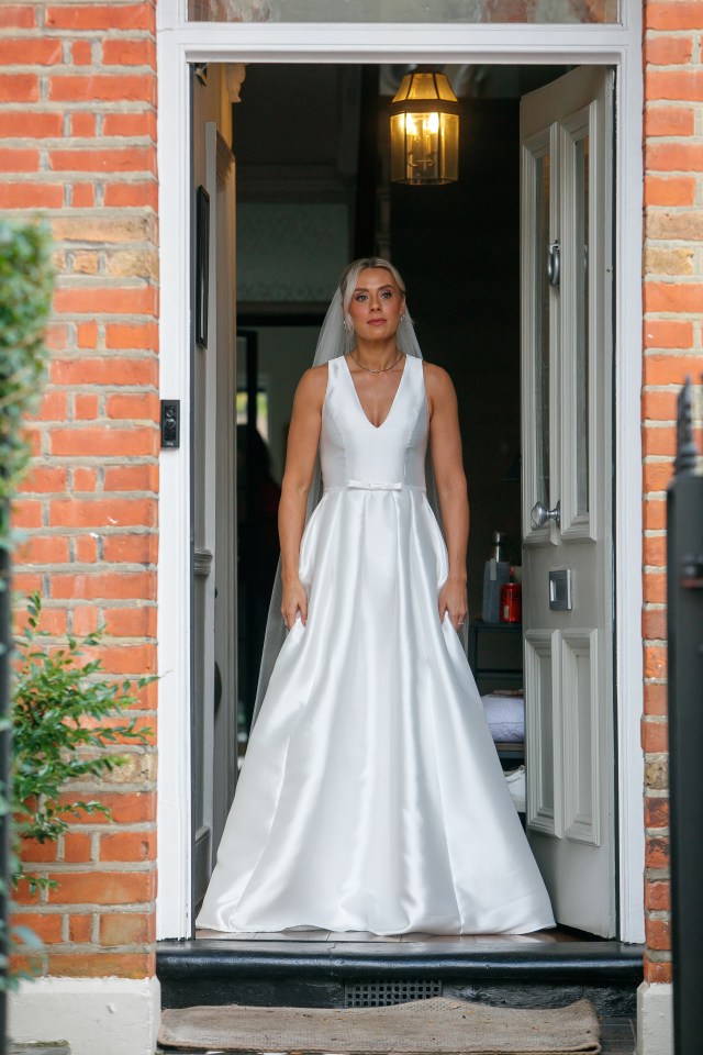 Bride in a white wedding dress standing in a doorway.