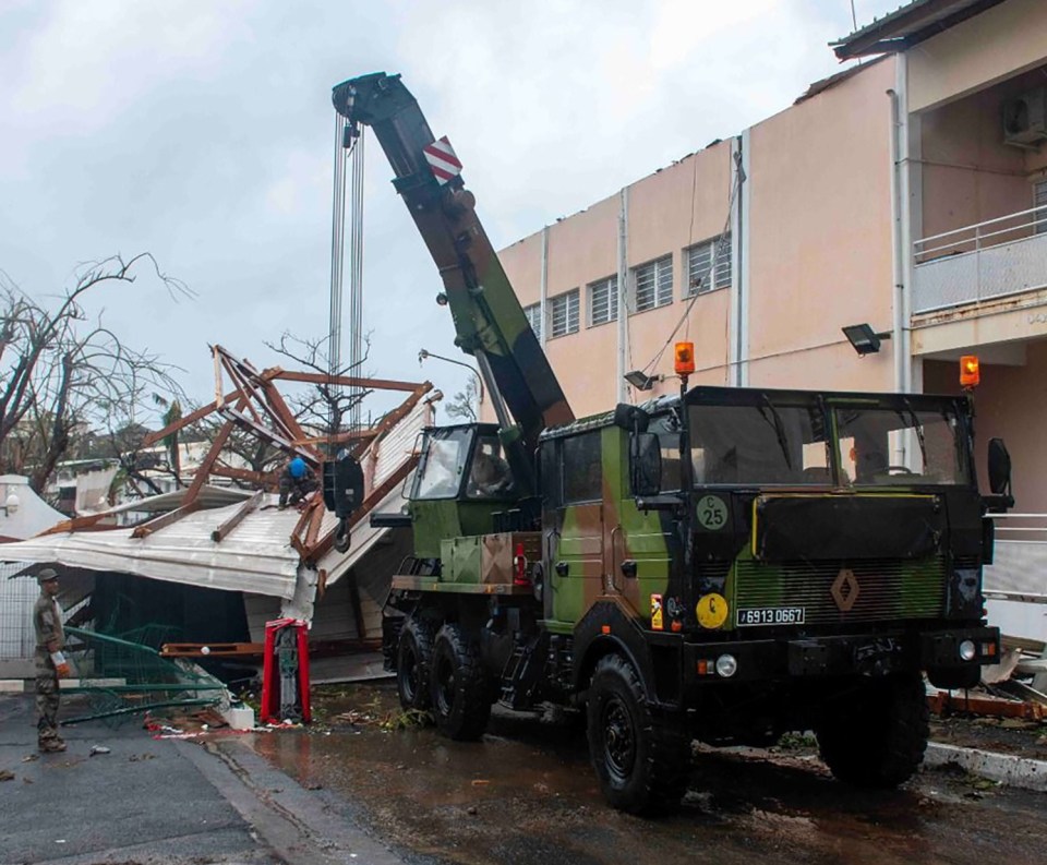 Soldiers remove debris from a damaged building in Mayotte following a cyclone.