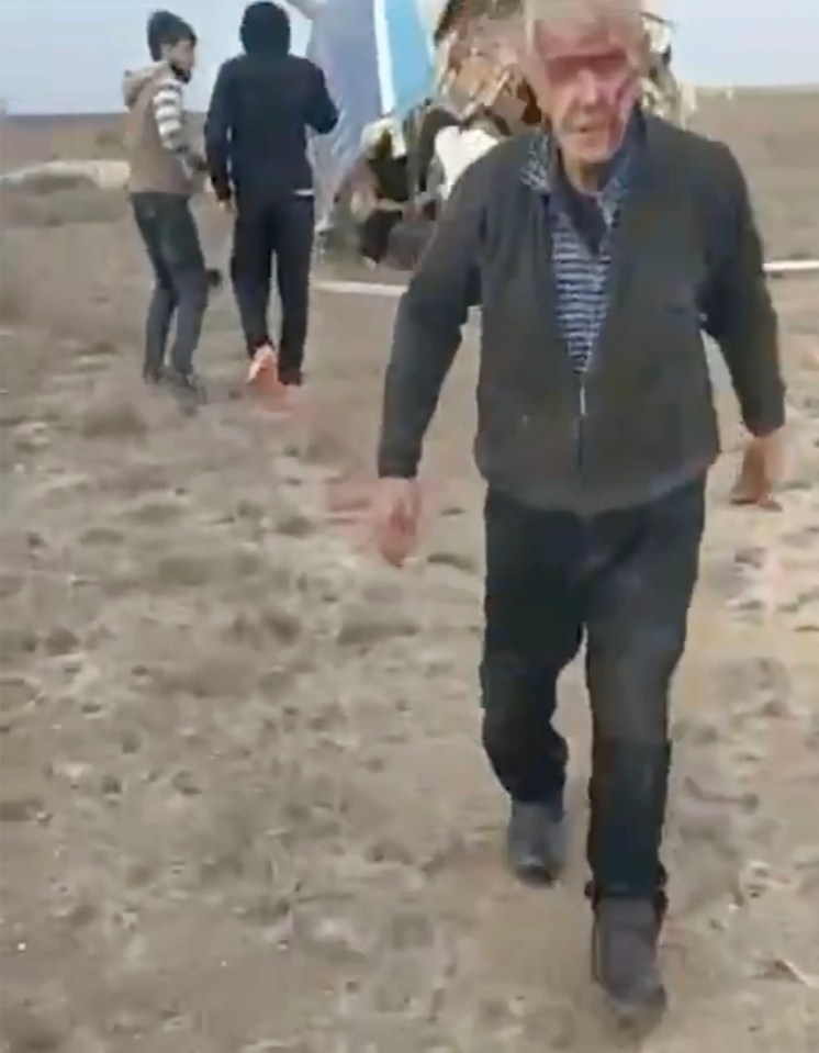 An injured man walks away from a crashed Azerbaijan Airlines plane.
