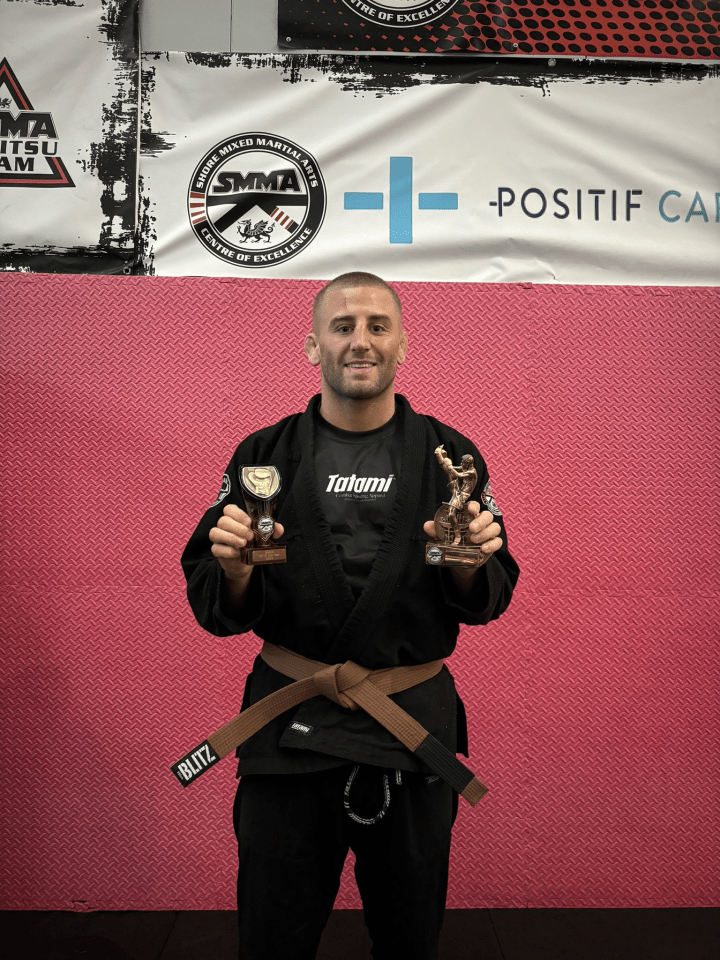 Martial arts competitor holding two trophies.
