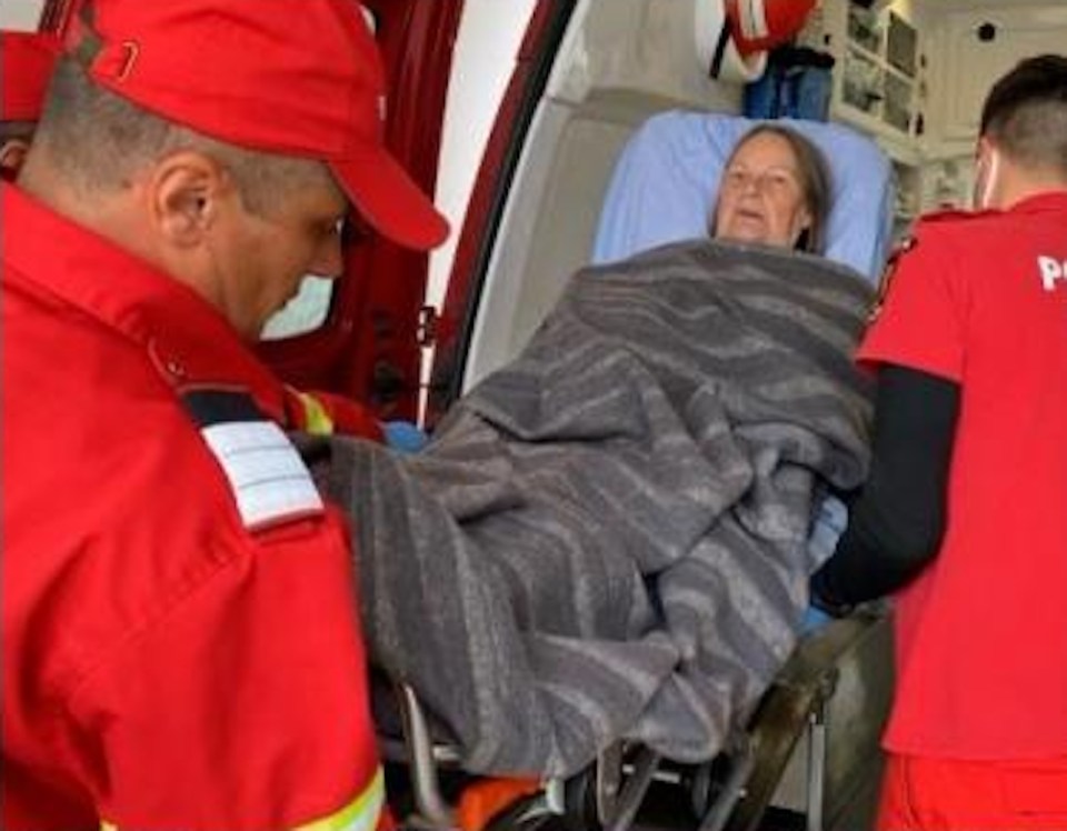 Paramedics assisting an elderly woman in an ambulance.