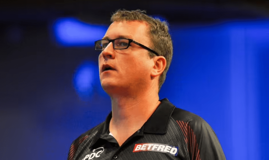A man wearing glasses and a Betfred shirt.