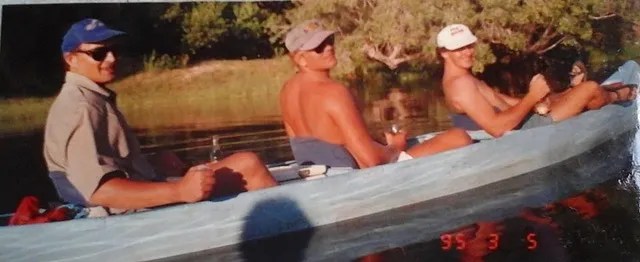 Three men in a canoe on a river.