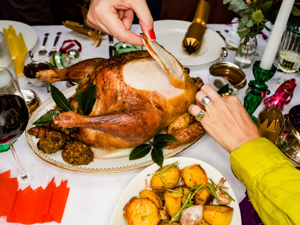 Friends carving a roasted turkey at a Christmas dinner.