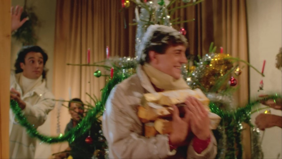 Scene from the "Last Christmas" music video: George Michael carries firewood while others decorate a Christmas tree.