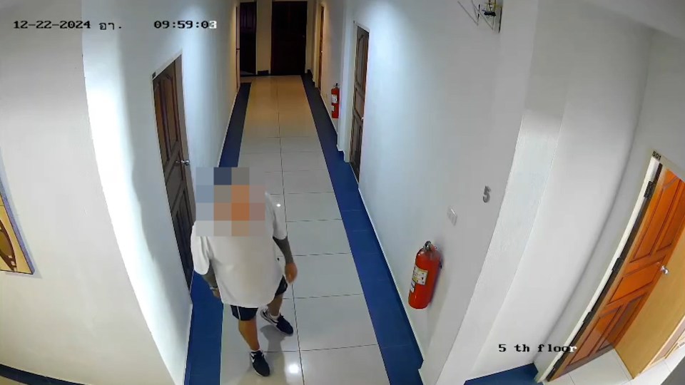 CCTV footage of a man walking down a hotel corridor.