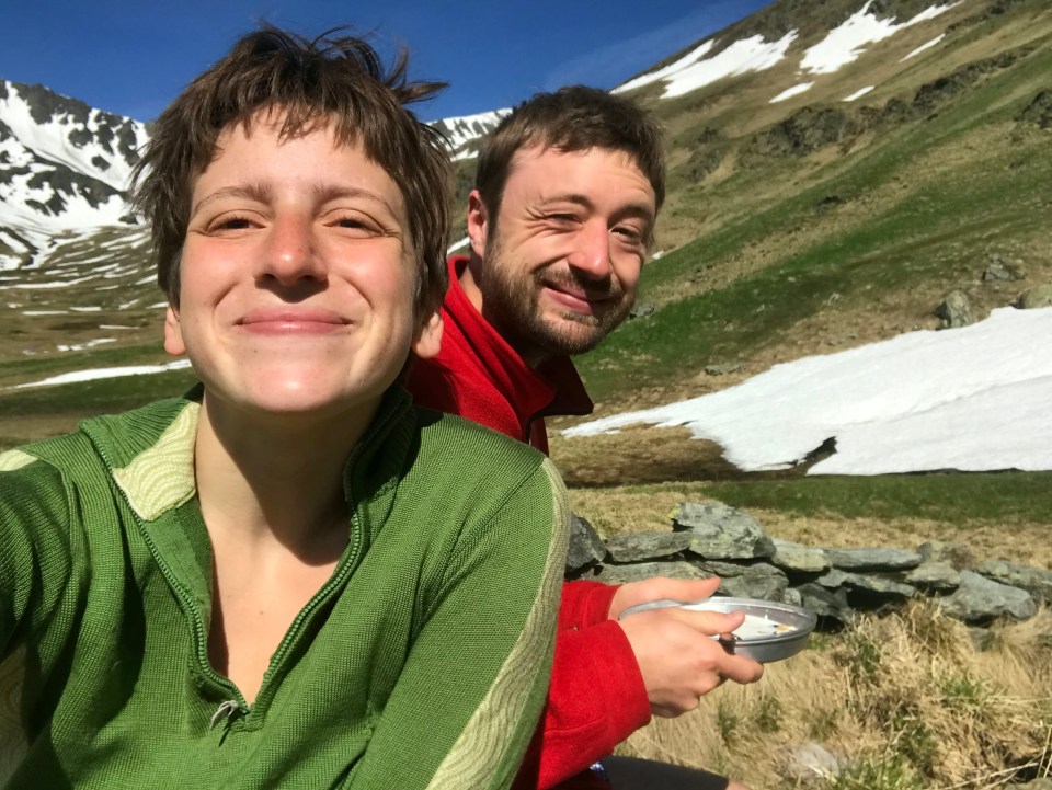 Two hikers smiling for a selfie in the mountains.
