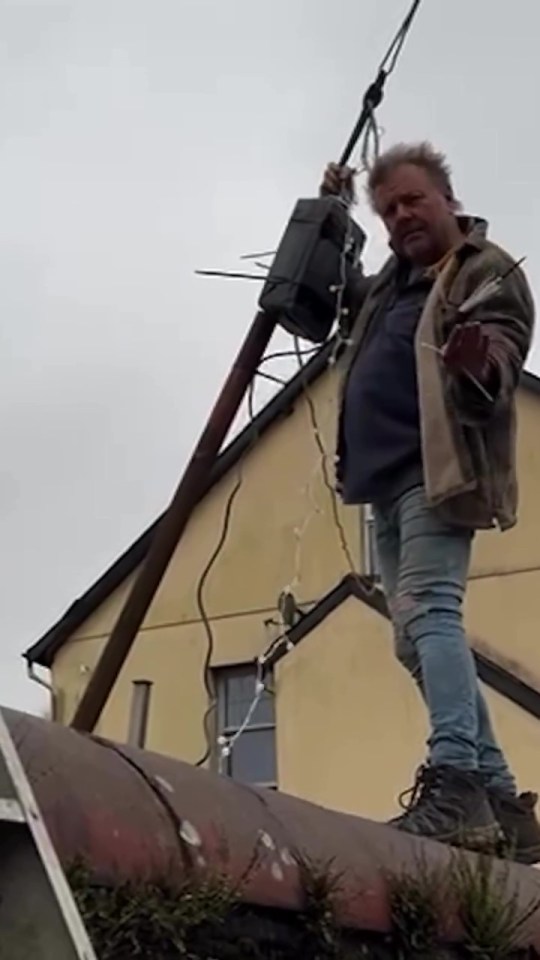 Man on a roof working on a utility pole.