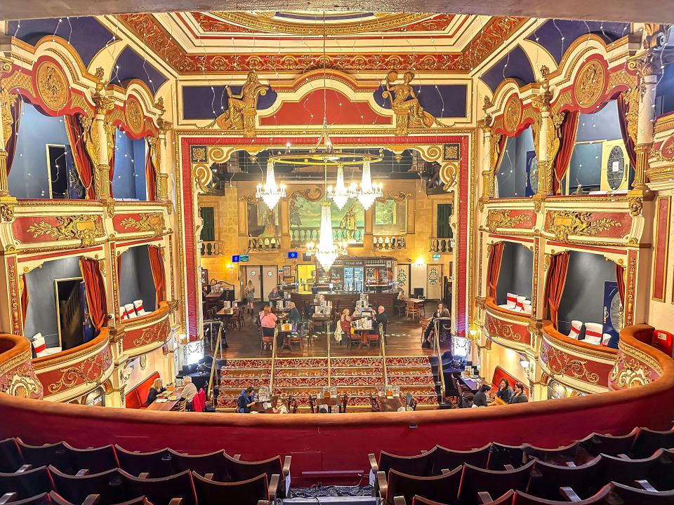 Interior view of a restored opera house, now a pub, showing the stage and audience seating.