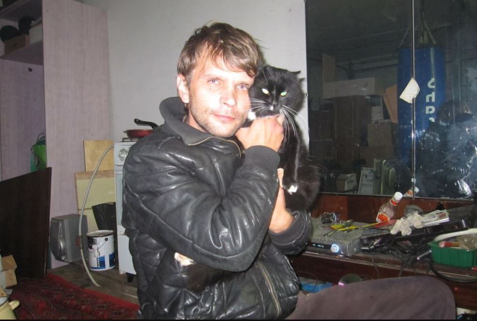 Man in leather jacket holding a black cat.