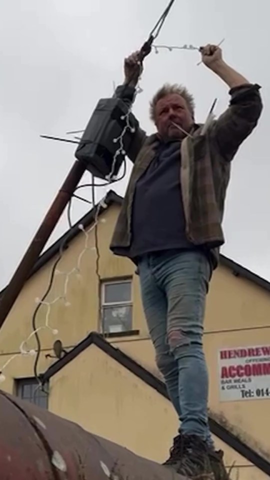 Man hanging Christmas lights on a pole.