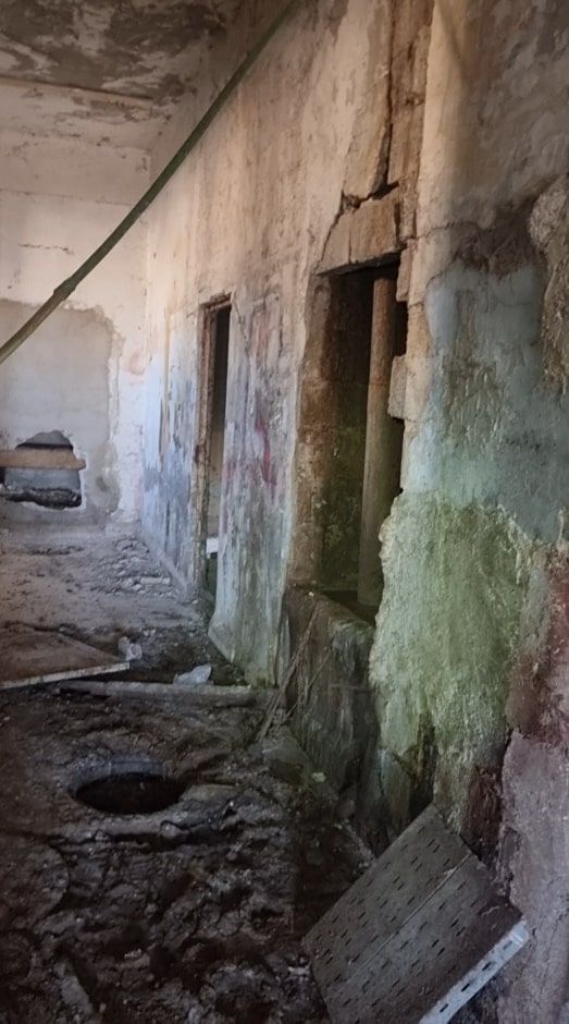 Interior of Assad's "butcher room," showing a dilapidated building with damaged walls and a hole in the floor.