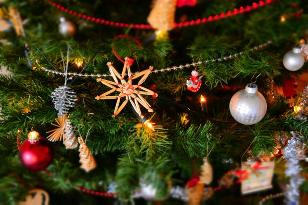 Close-up of a decorated Christmas tree with ornaments, lights, and a straw star.