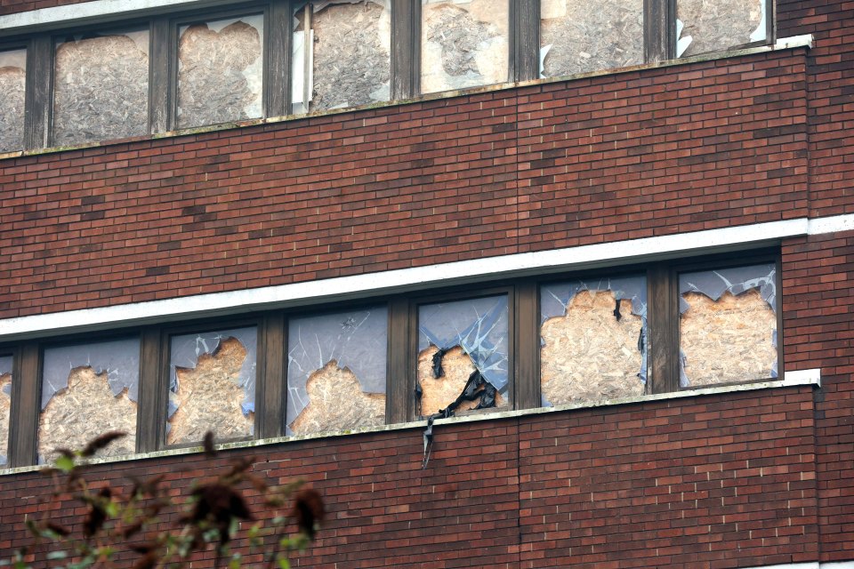 Boarded-up windows of a brick building.