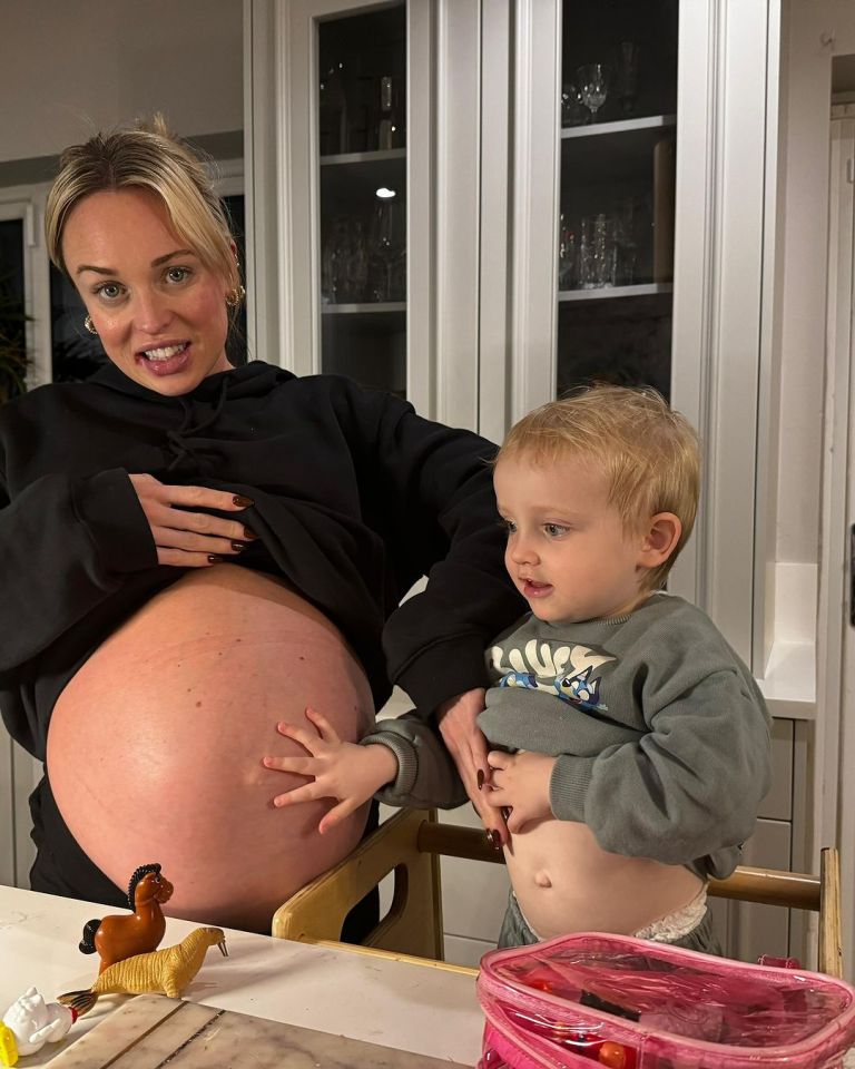 Pregnant woman with her toddler son touching her large baby bump.
