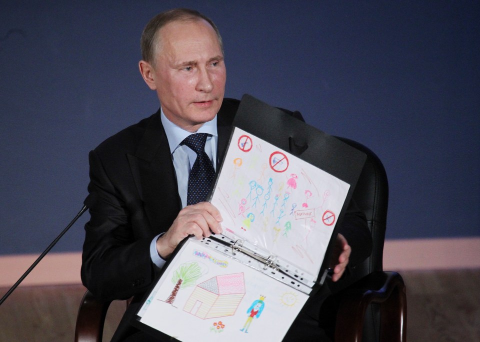 Vladimir Putin holding children's drawings at a meeting with students.
