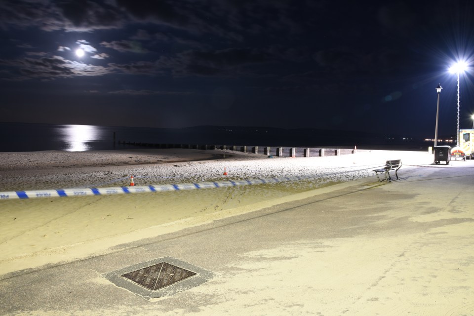 Nighttime view of a Bournemouth beach crime scene, cordoned off with police tape.