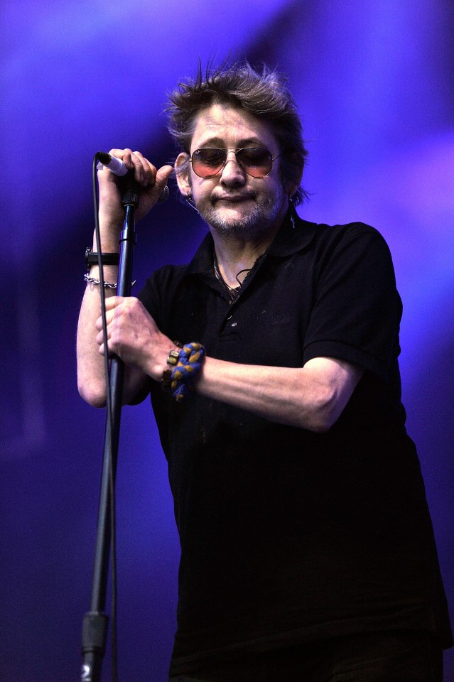 Shane MacGowan of The Pogues performing on stage.