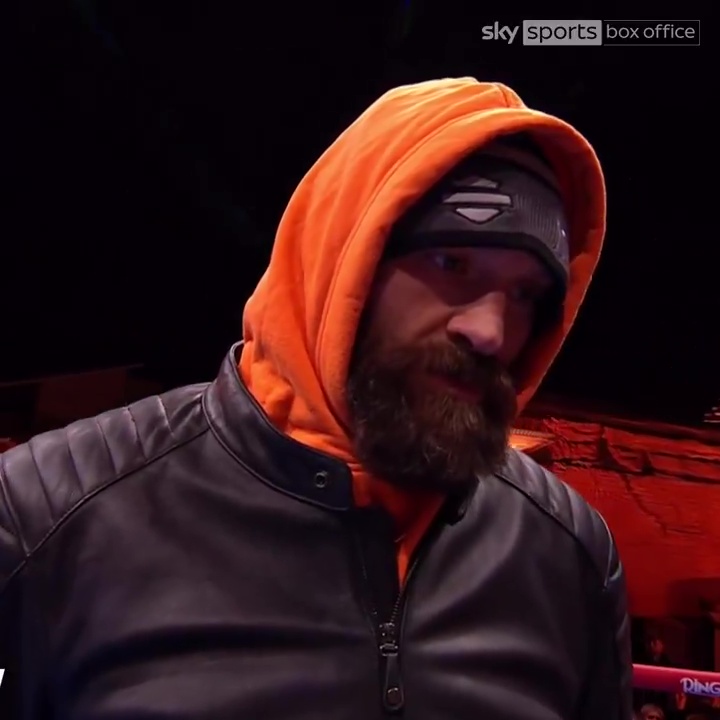 Tyson Fury in an orange hoodie and black leather jacket.