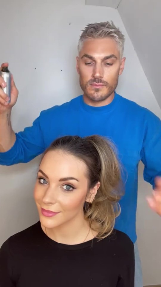 A man styles a woman's hair into a voluminous ponytail.
