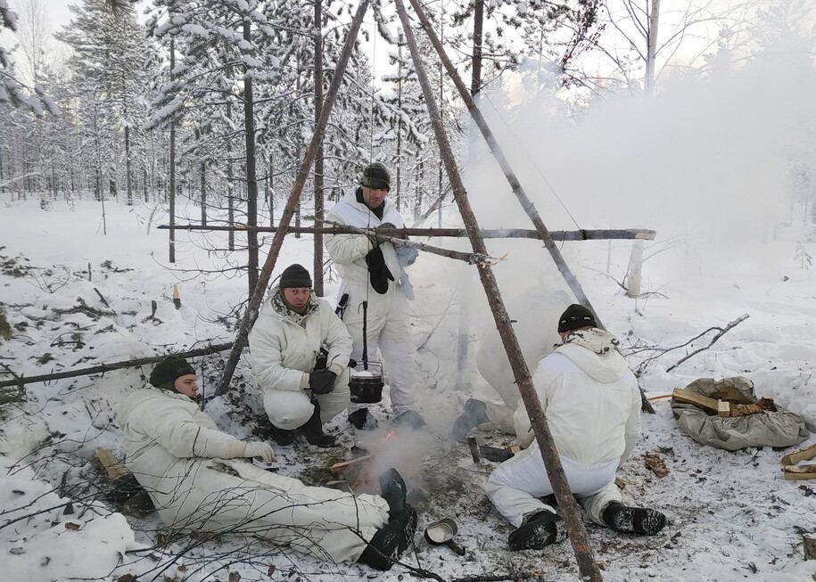 Soldiers building a fire in a snowy forest.