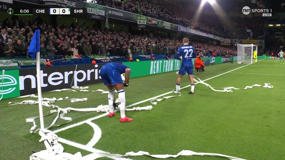 Soccer players cleaning up white tape on the field.