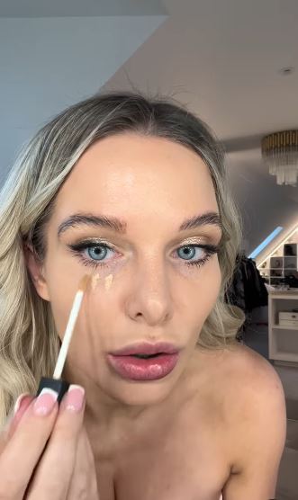 Woman applying concealer under her eyes.