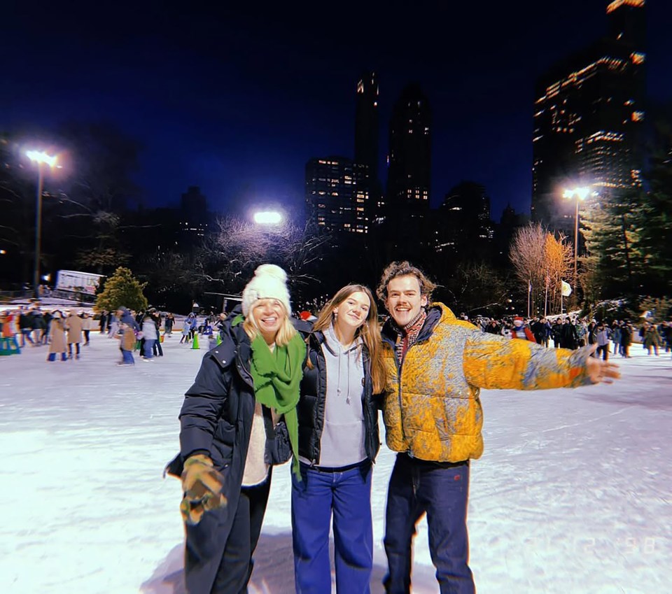 Three people ice skating at night in New York City.