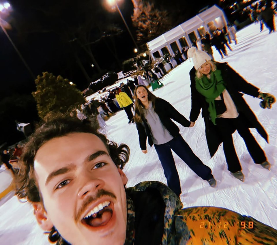 A selfie of a young man ice skating with two women.