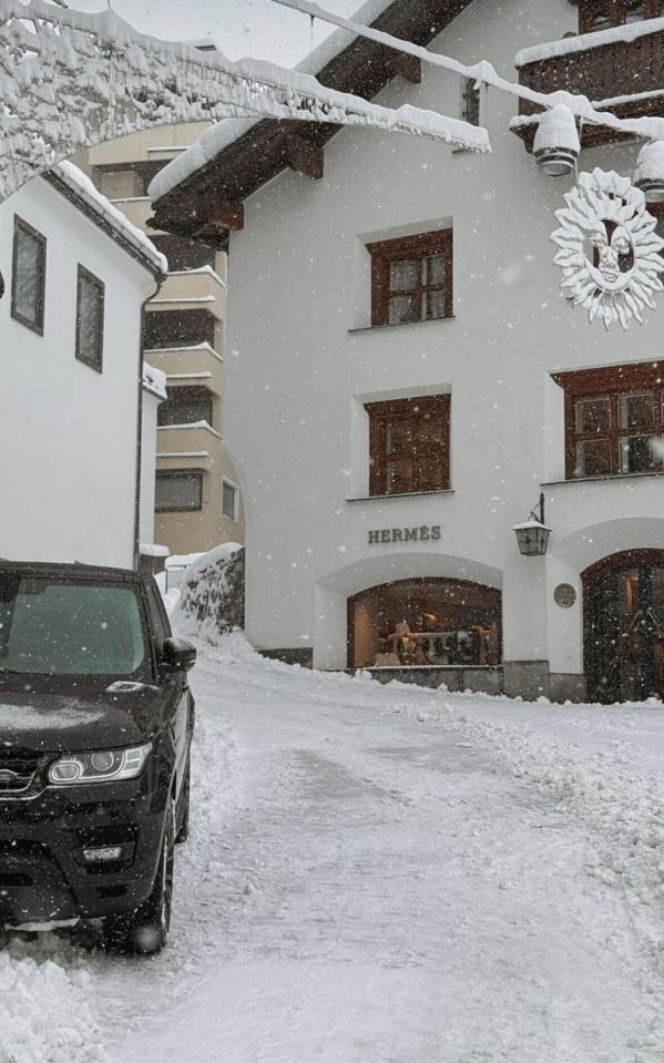 Black SUV parked in front of a snow-covered Hermès store.