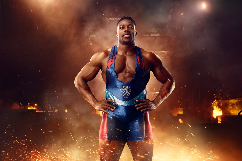 Muscular male wrestler in a blue singlet against a fiery background.