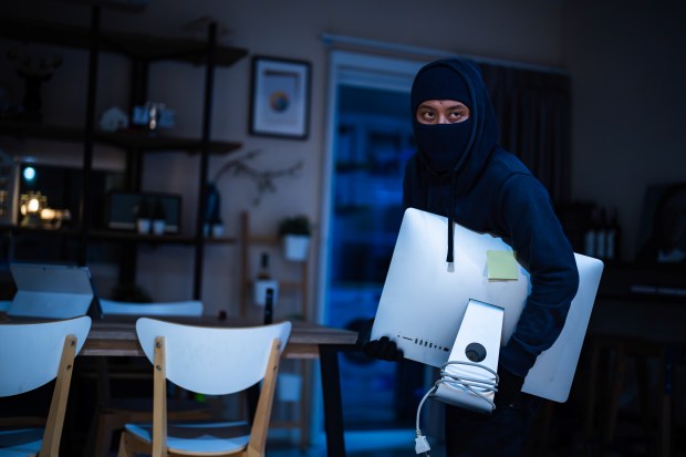 A burglar stealing a computer monitor from a house.