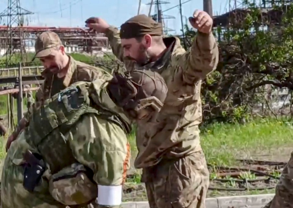 Russian soldiers escorting a surrendering Ukrainian soldier.