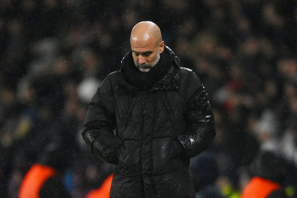 Pep Guardiola, Manchester City manager, looking down during a rain-soaked game.