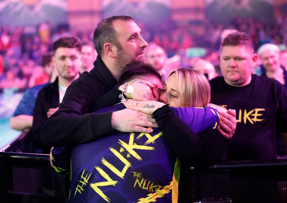 Luke Littler embraces his parents after a darts match victory.
