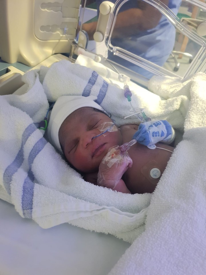 Newborn baby in hospital crib.