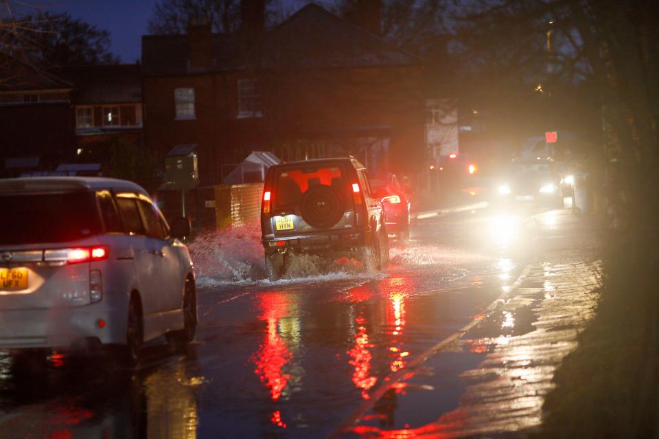 Cars driving through floodwaters at night.