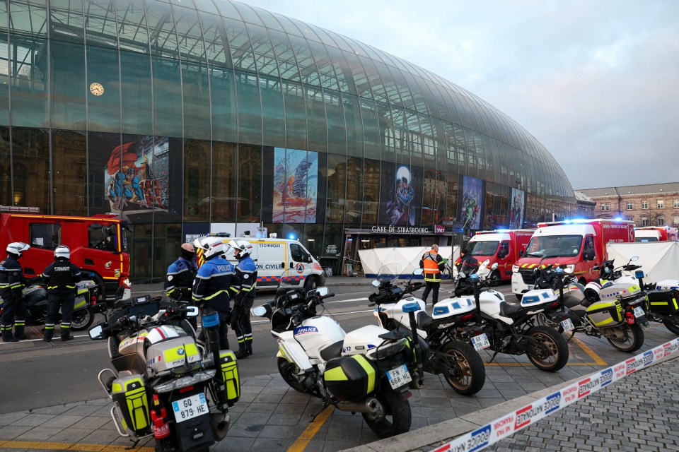 Police officers and emergency vehicles outside a train station after a tram collision.