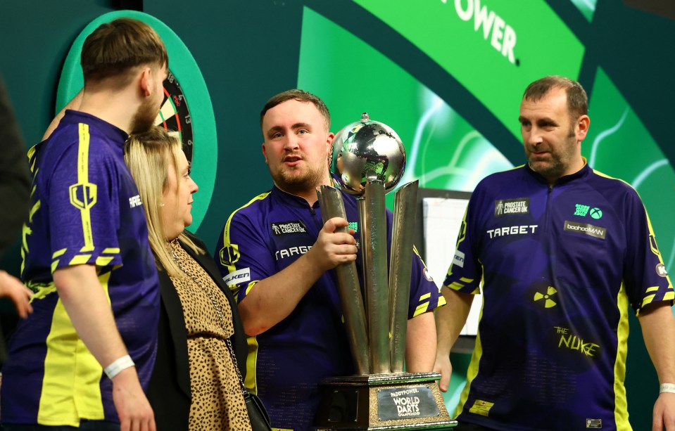 Luke Littler with his family and the PDC World Darts Championship trophy.