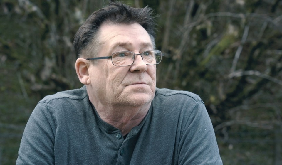 Man wearing glasses, looking off to the side.