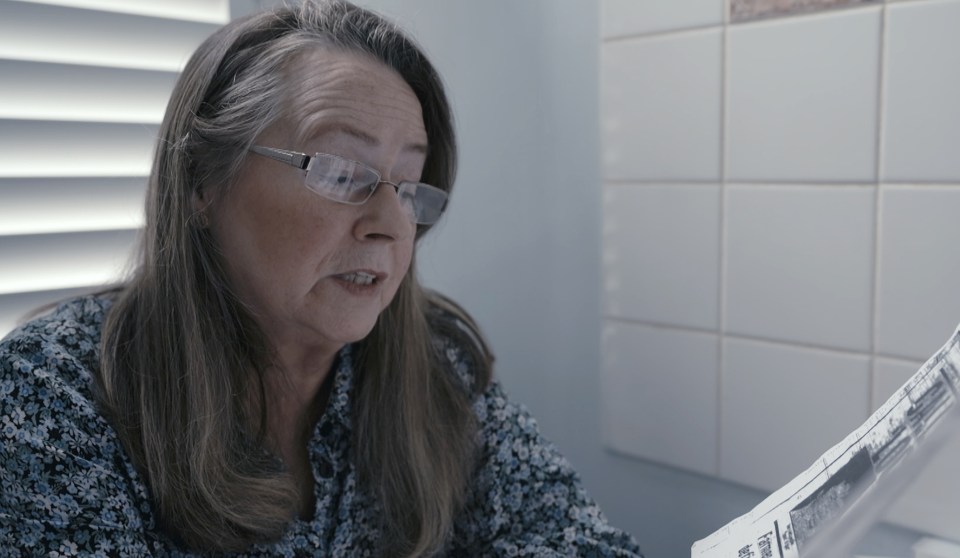 A woman reads a newspaper about her mother's murder.
