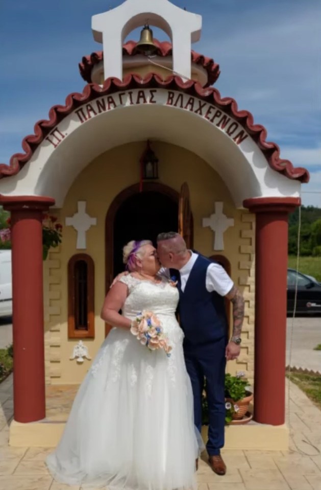 Bride and groom kissing in front of a small chapel.