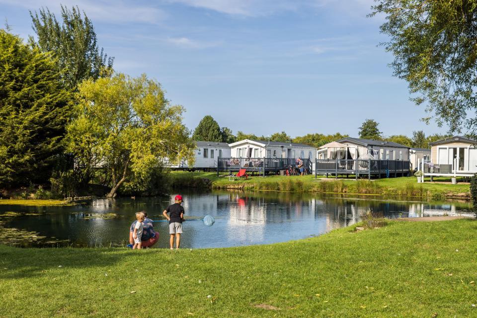 Family fishing by a pond at a holiday park.
