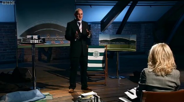 Man in suit presenting stadium plans to a woman.
