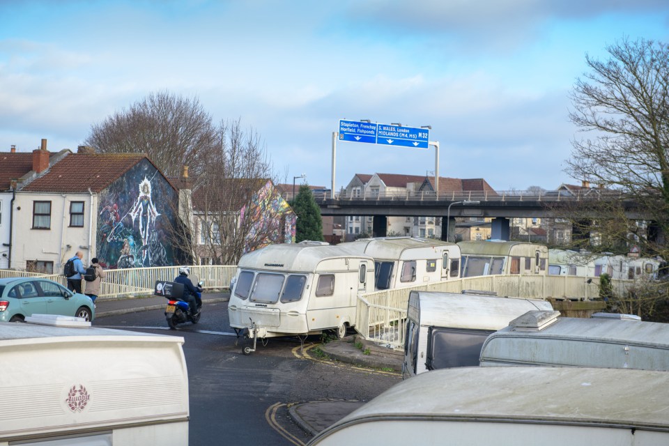 Caravans parked near a highway overpass.