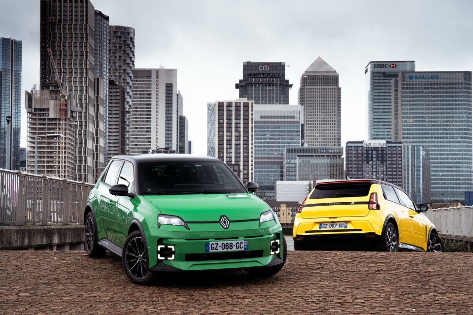 Two electric cars parked in front of a city skyline.