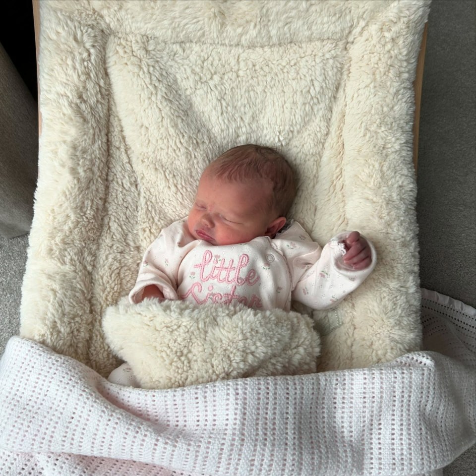 Newborn baby sleeping in a cream-colored baby swing.