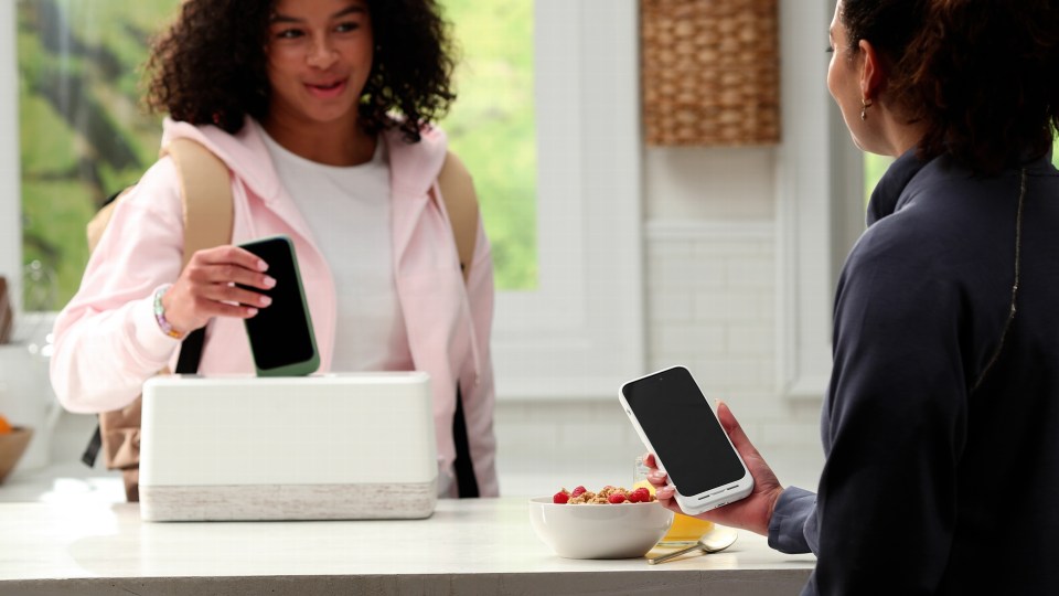 Two people exchanging smartphones.