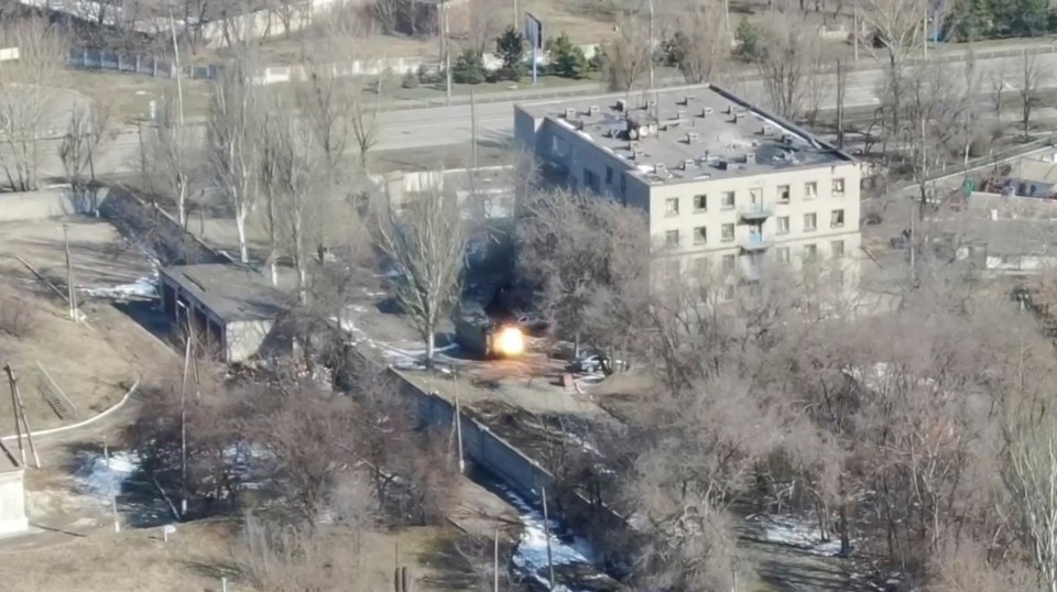 Aerial view of an armored vehicle firing near a building in Mariupol, Ukraine.